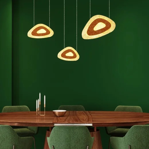 Essbereich mit grüner Wand, Holztisch, Sitzbank und drei orangefarbenen Pendelleuchten von KARE.